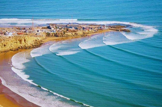 A wide sandy beach in Essaouira with people walking along the shore.