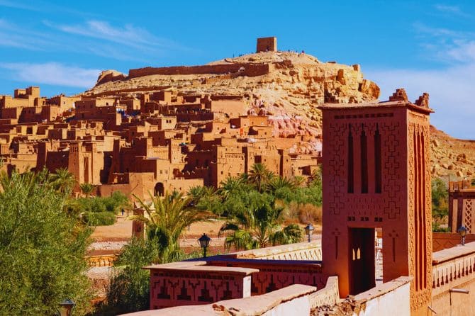 Traditional earthen buildings of Kasbah Ait Ben Haddou under a blue sky.