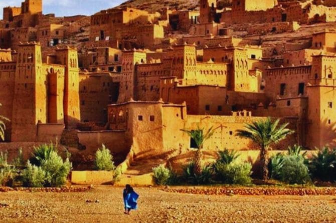 Traditional earthen buildings of Kasbah Ait Ben Haddou under a blue sky.